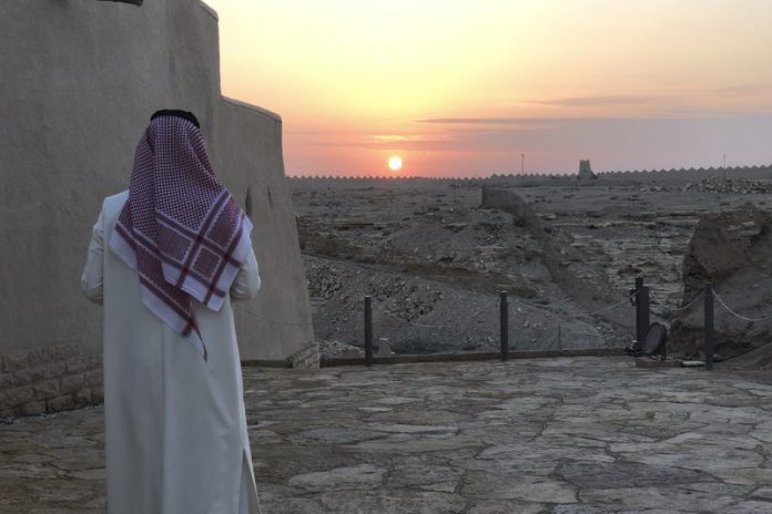 Saoedische man ziet de zon ondergaan in Dhiriyah, een 17e-eeuws fort dat op de werelderfgoedlijst van UNESCO staat. © AP Photo, Karin Laub